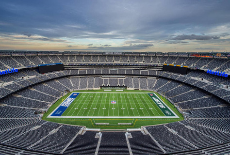 Bovenaanzicht van het lege MetLife Stadium met groen American football veld en rijen tribunes onder een bewolkte lucht