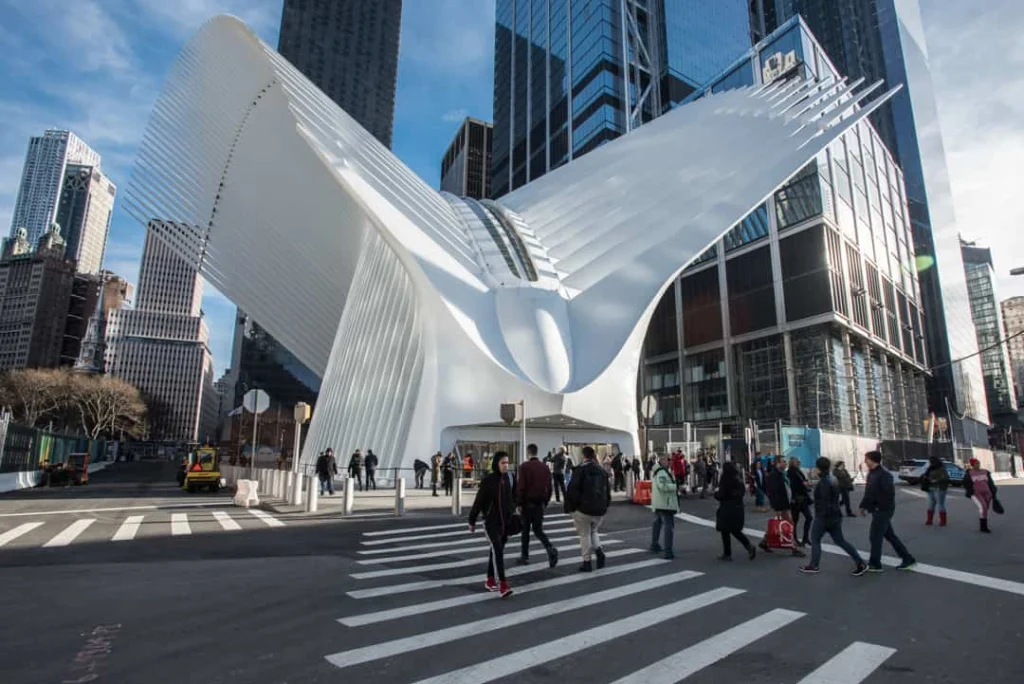 Het opvallende witte gebouw The Oculus bij het World Trade Center in New York met een vleugelvormige constructie, omringd door wolkenkrabbers en voetgangers op straat