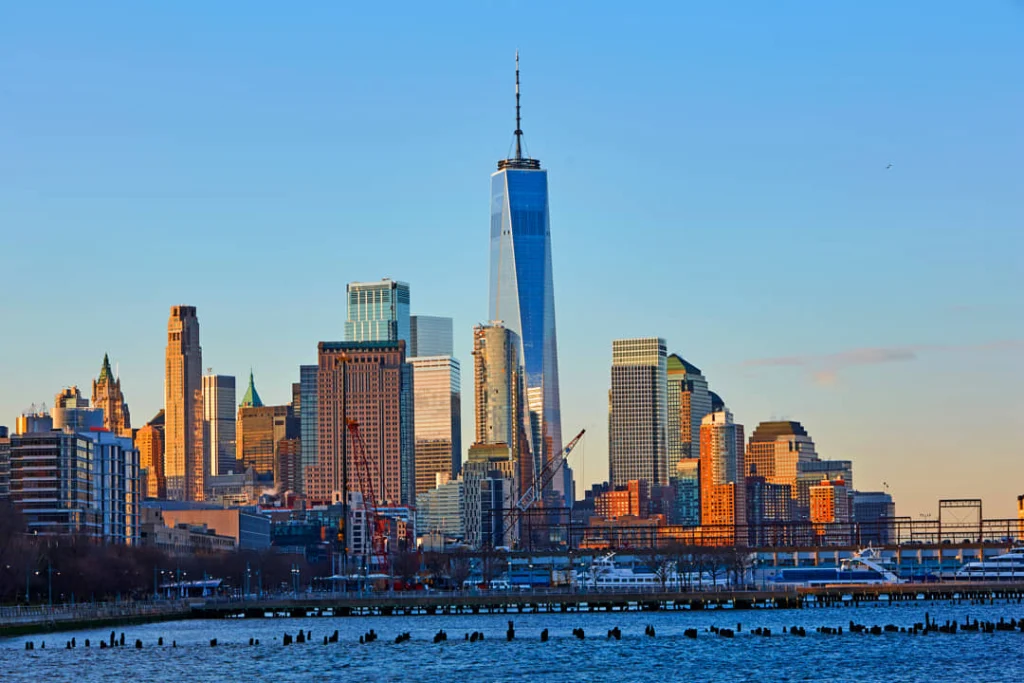 Wolkenkrabbers van Lower Manhattan gezien vanaf het water bij zonsondergang met One World Trade Center die boven de rest uitsteekt