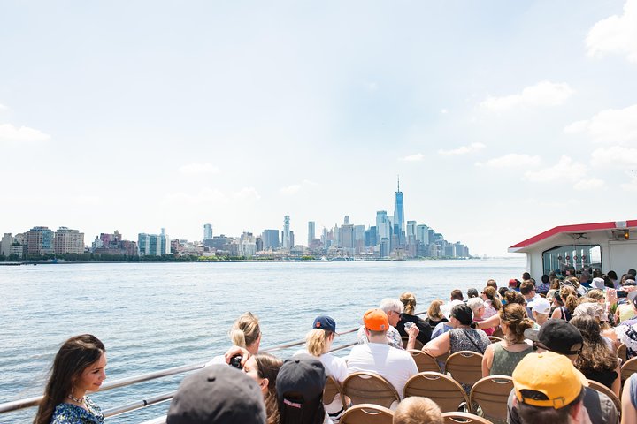 Passagiers op het dek van een veerboot kijken uit over de skyline van Manhattan aan de overkant van het water