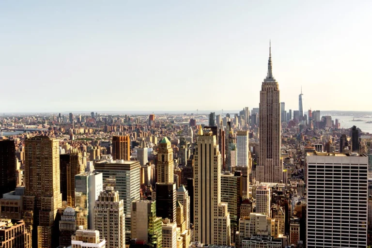 Uitzicht over de wolkenkrabbers van Manhattan vanaf Top of the Rock met het Empire State Building dat oplicht in warm middaglicht