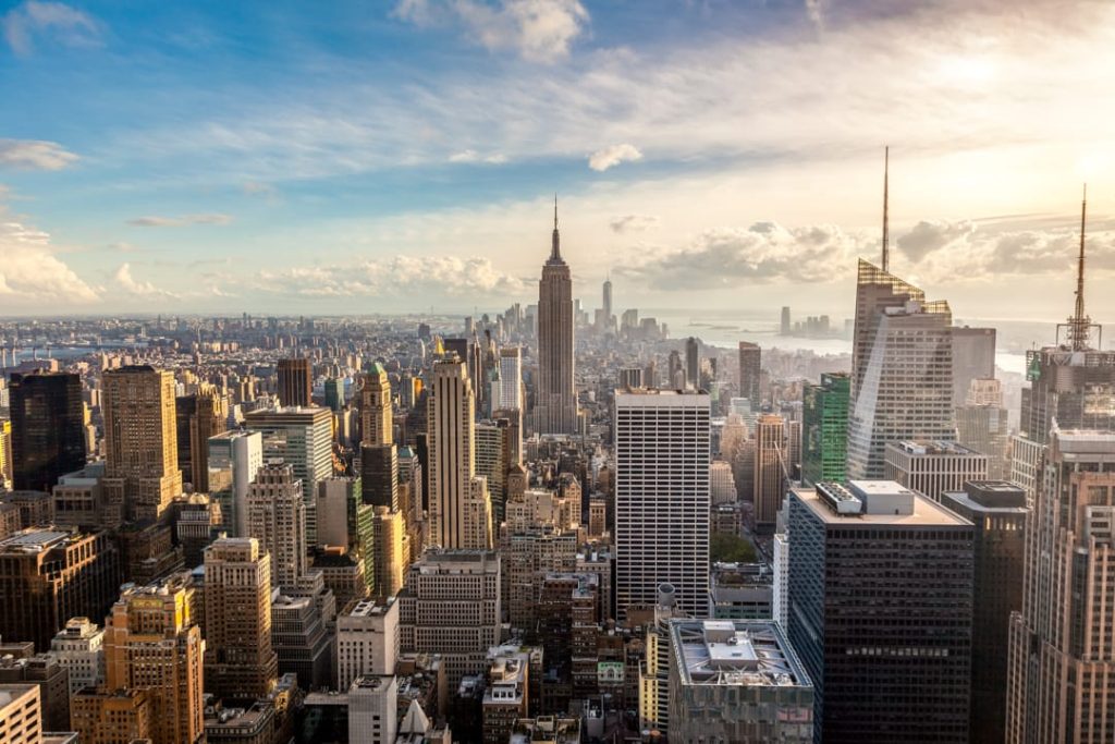 Uitzicht vanaf een hoog gebouw over de dichte skyline van Manhattan met het Empire State Building op de voorgrond bij zonsopgang