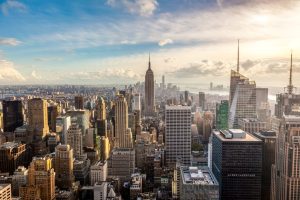 Uitzicht vanaf een hoog gebouw over de dichte skyline van Manhattan met het Empire State Building op de voorgrond bij zonsopgang