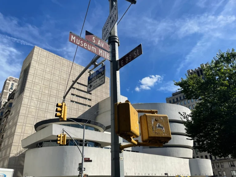Straatbordjes met de tekst 5 Av, Museum Mile en E 89 St met de ronde gevel van het Guggenheim Museum op de achtergrond