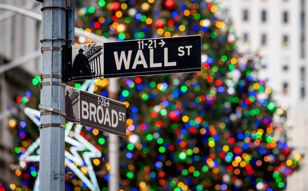 Straatnaambordjes met de teksten Wall Street en Broad Street voor een wazige achtergrond van kleurrijke kerstverlichting