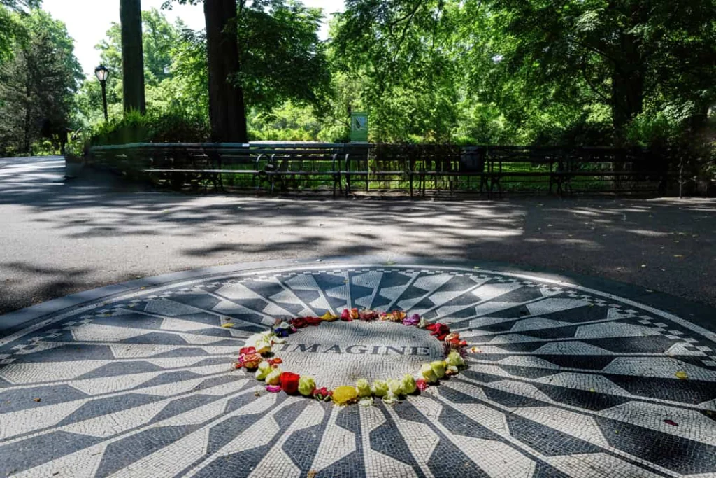 Zwart wit mozaïek met het woord Imagine op een pad in Central Park, omringd door bomen en bankjes