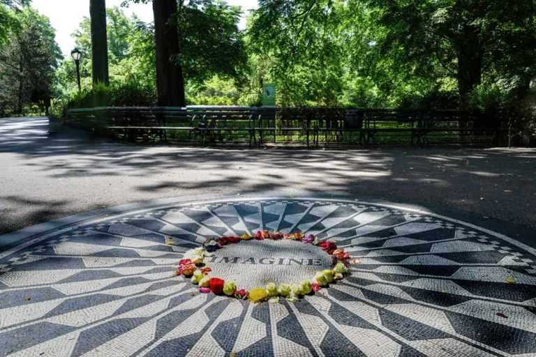 Zwart wit mozaïek met het woord Imagine op een pad in Central Park, omringd door bomen en bankjes