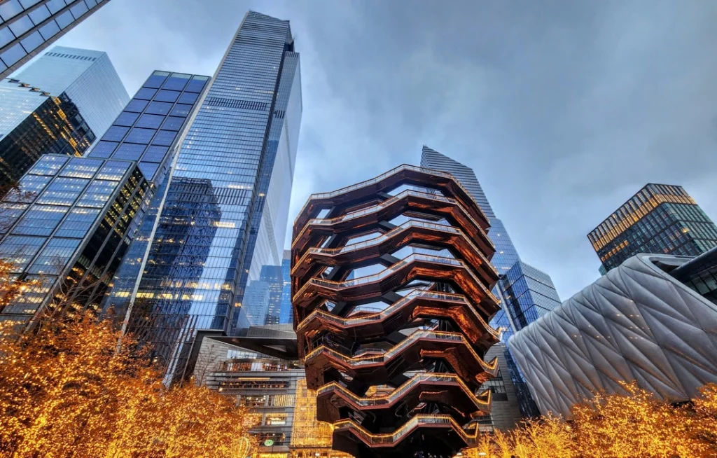 Bronskleurige honingraatstructuur The Vessel met trappen, omringd door hoge glazen wolkenkrabbers in Hudson Yards, New York
