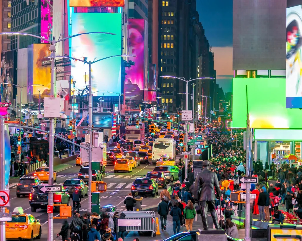 Drukke kruising van Times Square in New York met kleurrijke digitale billboards, verkeer en voetgangers in de avondschemering