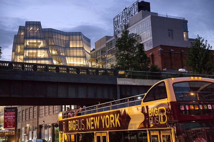 Een gele dubbeldekker toeristenbus rijdt in de schemering langs moderne glazen gebouwen in New York
