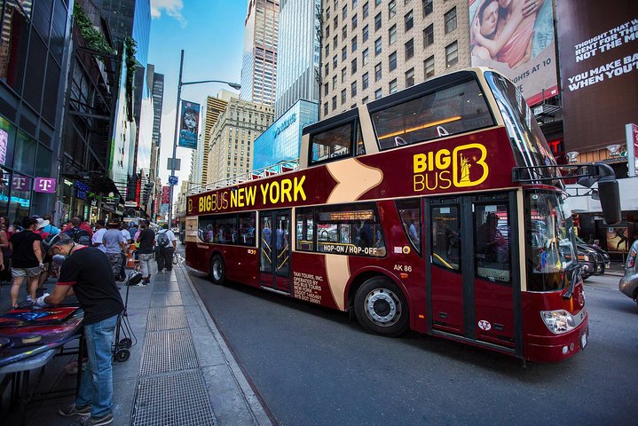 Een rode dubbeldekker toeristenbus staat geparkeerd tussen de felverlichte reclameborden op Times Square in New York