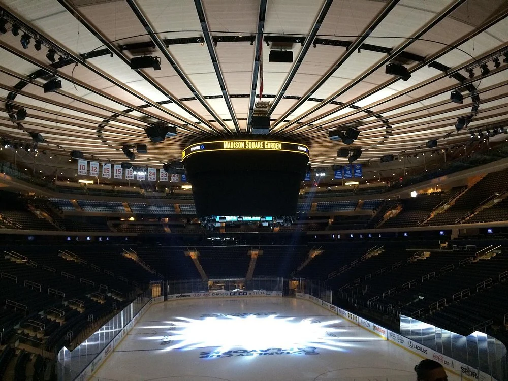 Uitzicht vanaf hoge tribuneplaatsen op de ijsbaan van Madison Square Garden met hangende vaandels van gepensioneerde rugnummers