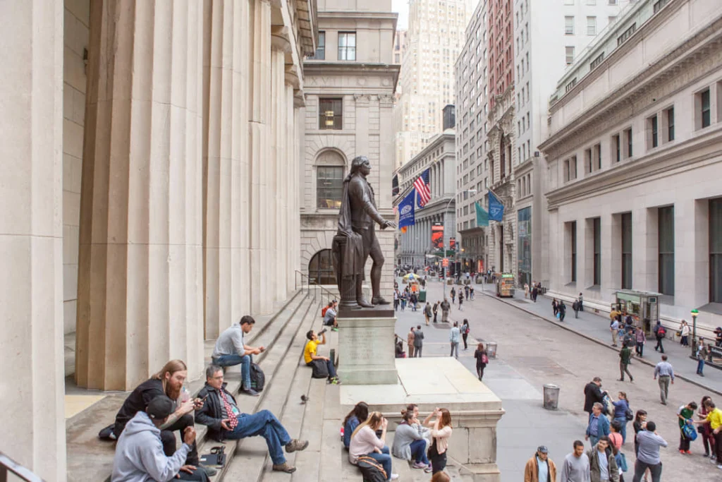 Uitzicht vanaf de zuilengalerij van Federal Hall over Wall Street met het standbeeld van George Washington en wandelende mensen