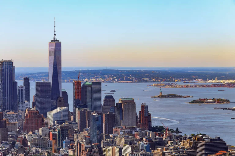 Panoramisch uitzicht vanaf een observatiedek over de wolkenkrabbers van Lower Manhattan met de baai en het Vrijheidsbeeld in de verte
