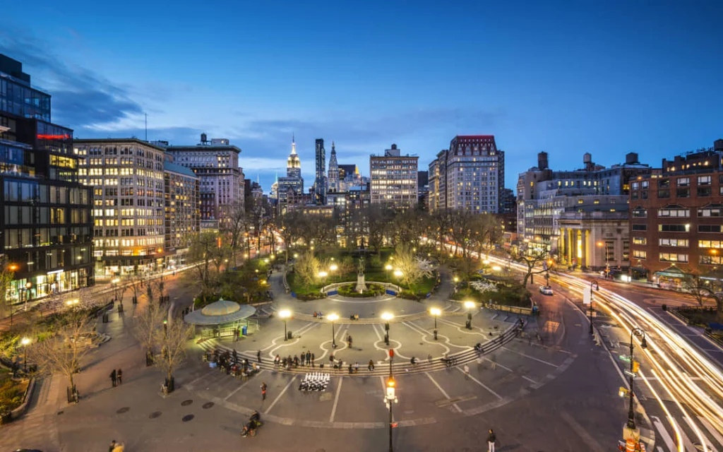 Luchtzicht op Union Square in New York bij schemering met lichtsporen van auto's en de skyline van Manhattan