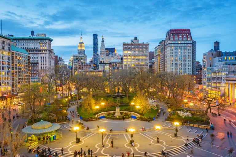 Luchtzicht op het groene Union Square Park in New York bij schemering met de verlichte skyline van Manhattan erachter