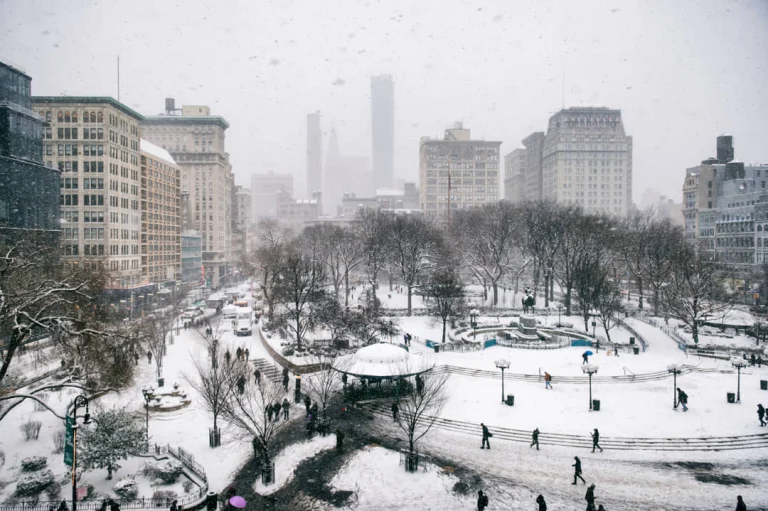 Luchtzicht op een besneeuwd Union Square Park in New York met kale bomen en de skyline van Manhattan