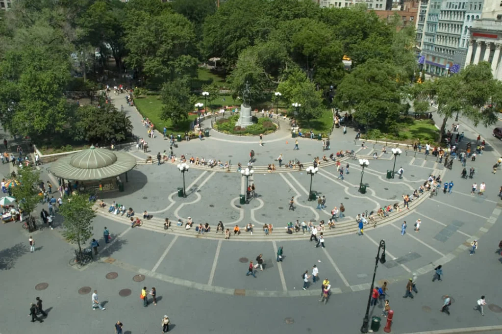 Luchtzicht op Union Square Park in New York overdag met groene bomen, een kiosk en tientallen wandelende bezoekers
