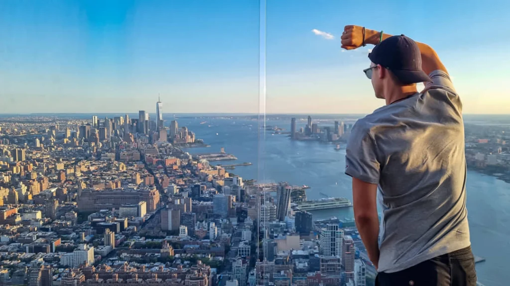 Rij wapperende vlaggen van verschillende landen tegen een blauwe lucht met kantoorgebouwen van het Rockefeller Center op de achtergrond