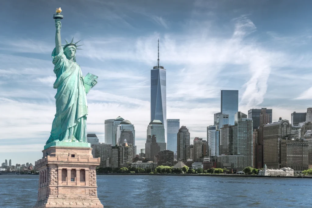 Het groene Vrijheidsbeeld op de voorgrond met de wolkenkrabbers van Lower Manhattan waaronder One World Trade Center op de achtergrond