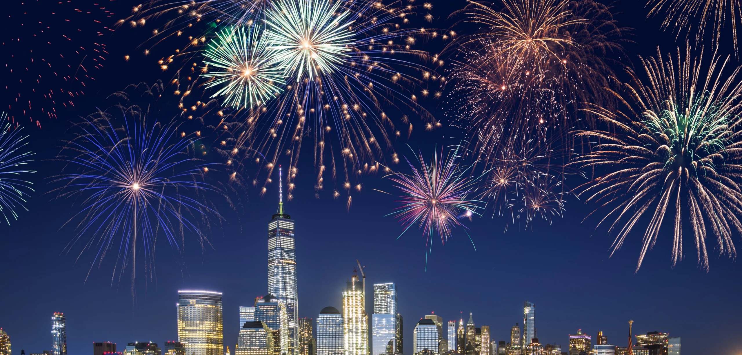 Kleurrijk vuurwerk boven de verlichte wolkenkrabbers van Manhattan met One World Trade Center in de nacht