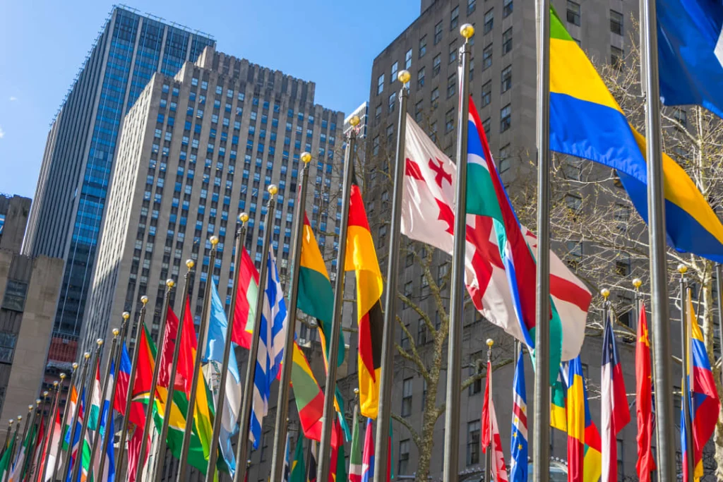 Close-up van felgekleurde nationale vlaggen die wapperen in de wind met hoge gebouwen van het Rockefeller Center op de achtergrond