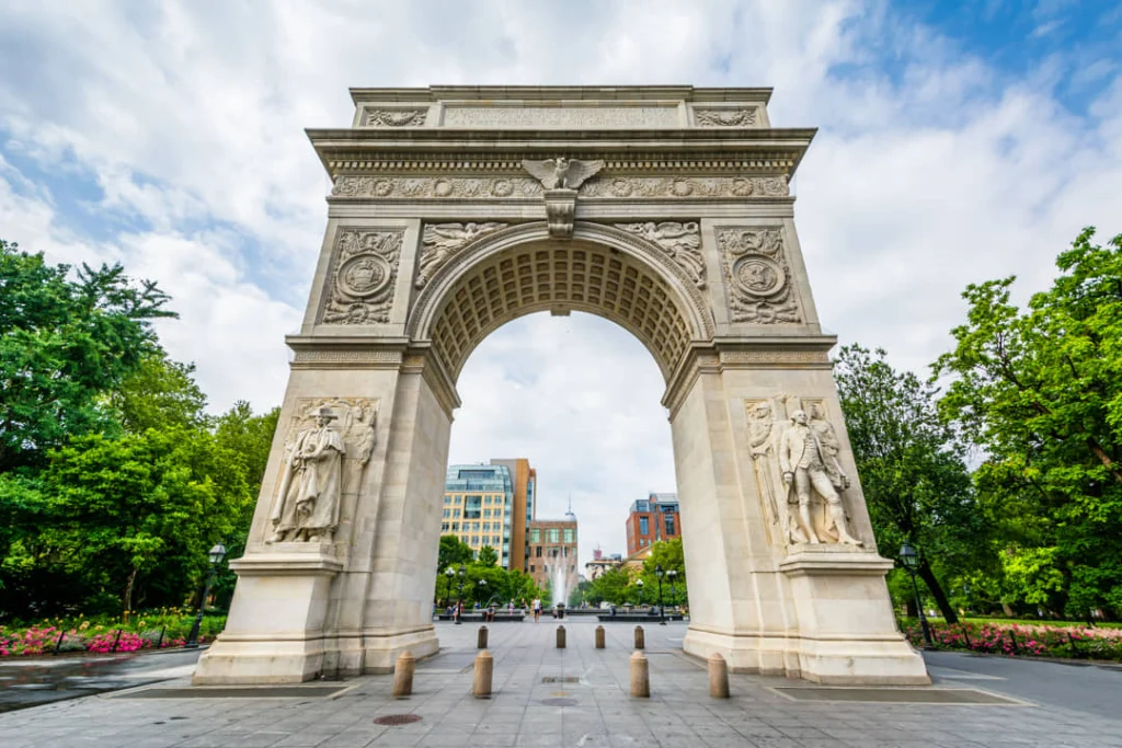 Close-up van de witte marmeren Washington Square boog in New York met gebeeldhouwde sierdetails onder een bewolkte lucht
