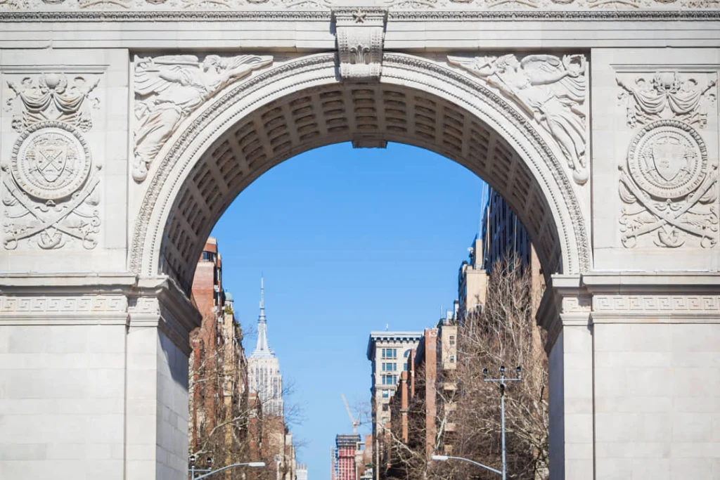 Close-up van de gebeeldhouwde Washington Square boog in New York met een doorkijk naar het Empire State Building