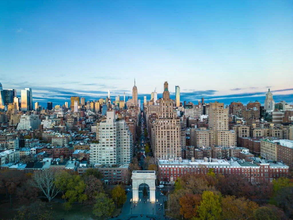 Luchtzicht op straten en gebouwen rond Washington Square Park in New York in herfstkleuren met de skyline van Manhattan