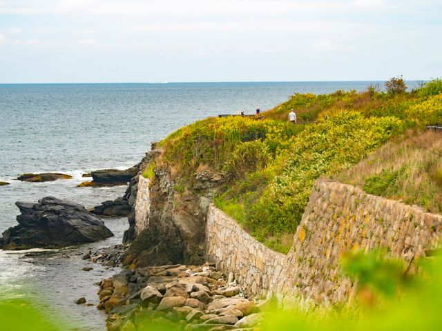 Wandelaars lopen over een pad met stenen muur langs de rotsachtige kust van de Cliff Walk in Newport, Rhode Island, met uitzicht over de oceaan