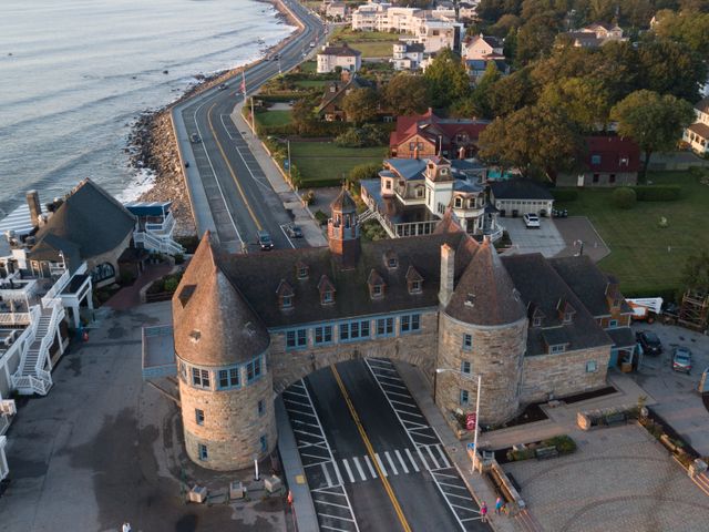 Luchtfoto van een stenen poortgebouw met twee ronde torens waar de kustweg onderdoor loopt, met de oceaan aan de ene kant en villa's aan de andere kant bij Newport, Rhode Island