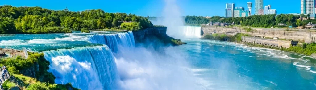 Brede, schuimende watervallen van Niagara Falls met wolkenkrabbers van de stad zichtbaar op de achtergrond