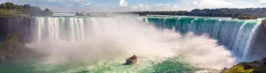 Een boot vol toeristen vaart door de opspattende nevel voor de hoefijzervormige Niagara watervallen in Canada