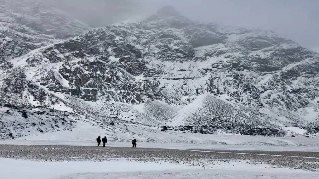 Drie kleine wandelaars lopen door een besneeuwd dal omringd door ruige bergen in Auyuittuq National Park in Nunavut