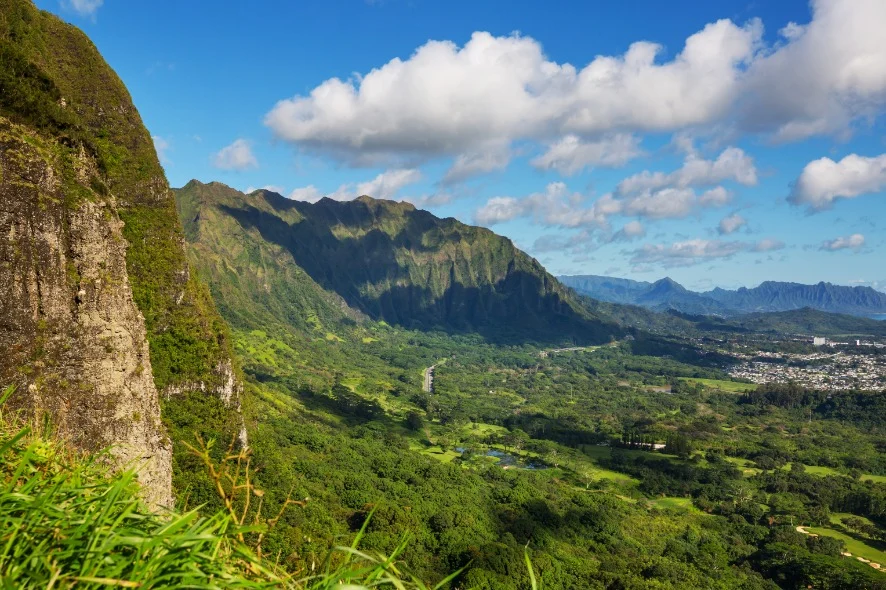 Weids uitzicht vanaf een bergkam over een groen begroeid dal met een woonwijk in de verte op Oahu