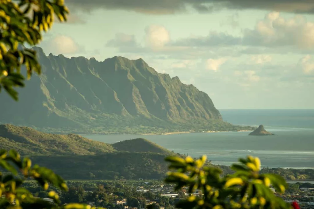 Groene, steil oprijzende bergketen van het Koolaugebergte op Oahu met een baai en klein rotseiland aan de kust