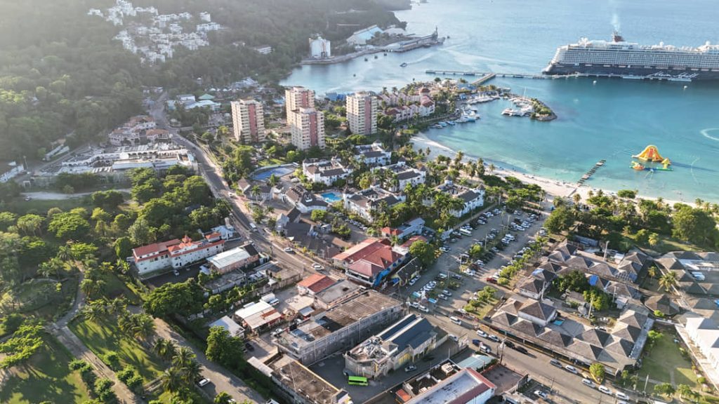 Luchtfoto van hotels en straten in Ocho Rios met een cruiseschip aangemeerd in de haven en een strand met waterattractie