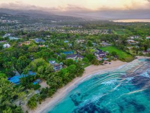 Luchtfoto van huizen en groen langs de kust van Ocho Rios met bergen en zee op de achtergrond bij een gouden avondlucht