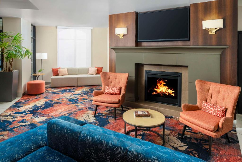 Gezellige hotellobby met een brandende openhaard, oranje fauteuils en een blauwe bank op een gepatroond tapijt