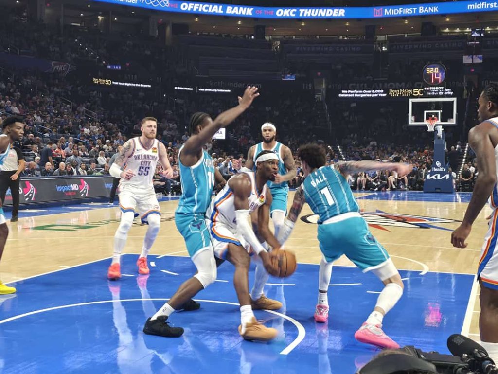 Basketbalspelers in actie onder de basket tijdens een wedstrijd van de Oklahoma City Thunder, met volle tribunes