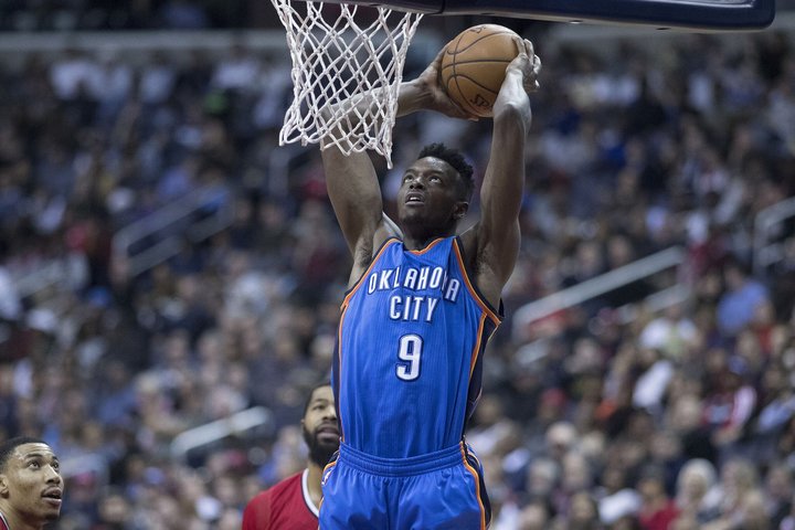Basketbalspeler in het shirt van Oklahoma City maakt een dunk aan de basket, publiek op de achtergrond
