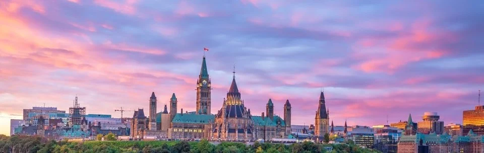 Silhouet van de torens van het Canadese parlementsgebouw in Ottawa tegen een roze en paarse avondlucht