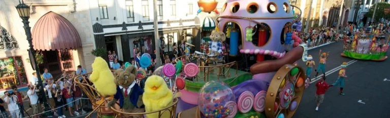 Een kleurrijk versierde parade wagen met pluche figuren rijdt door de straat van Universal Studios Florida terwijl bezoekers toekijken
