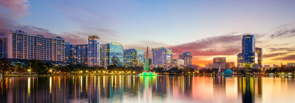 Verlichte wolkenkrabbers van Orlando weerspiegelen in het water van Lake Eola, omlijst door palmbomen bij avond