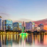 Verlichte wolkenkrabbers van Orlando weerspiegelen in het water van Lake Eola, omlijst door palmbomen bij avond