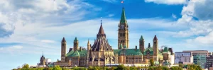 Het historische parlementsgebouw van Ottawa met de Peace Tower en groene koperen daken tegen een blauwe lucht met wolken