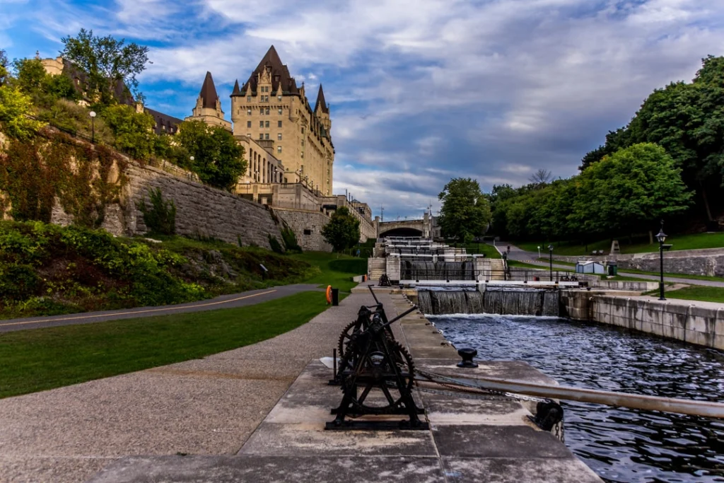 Trapsgewijze sluizen van het Rideaukanaal in Ottawa met het Château Laurier hotel op een heuvel onder een bewolkte lucht