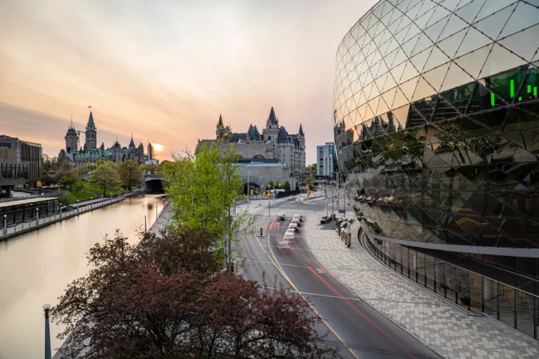 Weg langs het kanaal in Ottawa met het Château Laurier hotel, het parlementsgebouw en een modern glazen gebouw bij zonsondergang