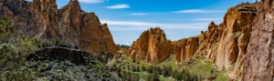 Uitzicht op ruige oranje rotsformaties en een groene canyon met rivier in de Pacific Northwest, met besneeuwde bergtoppen in de verte