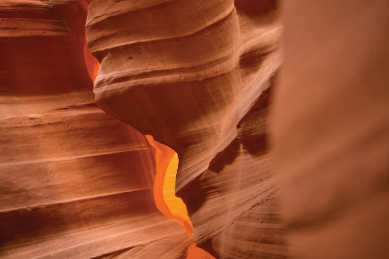 Gladde golvende roodoranje zandstenen wanden van een slotcanyon met een lichtstreep bij Antelope Canyon